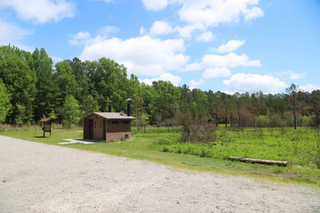 Parking lot with restrooms and open field at Longleaf Campground