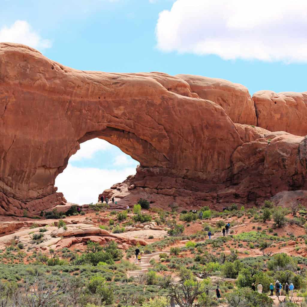 Photo of Double Arch in the Windows swction of Arches National Park with visitors hiking to the base of the Arch