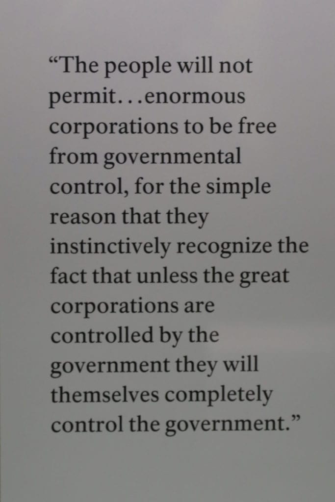 Theodore Roosevelt Quote posted on the wall "The people will not permit...enormous corporations to be free from governmental control, for the simple reason that they instinctively recgonize the fact that unless the great corporations are controlled by the government they will themselves completely control the government."