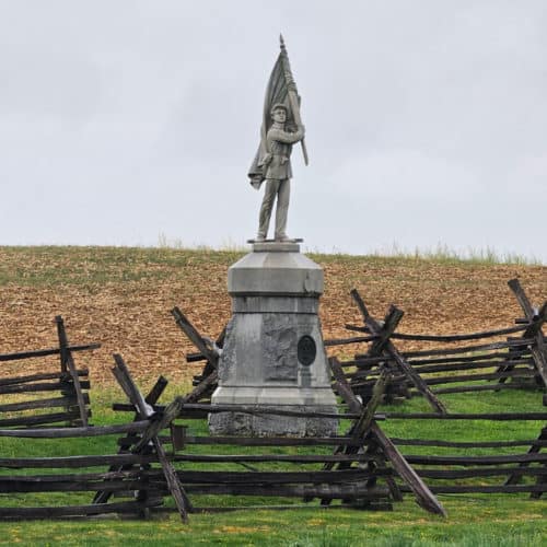 historic battlefield statue with a boy holding a flag surrounded by wooden fences in Antietam National Battlefield