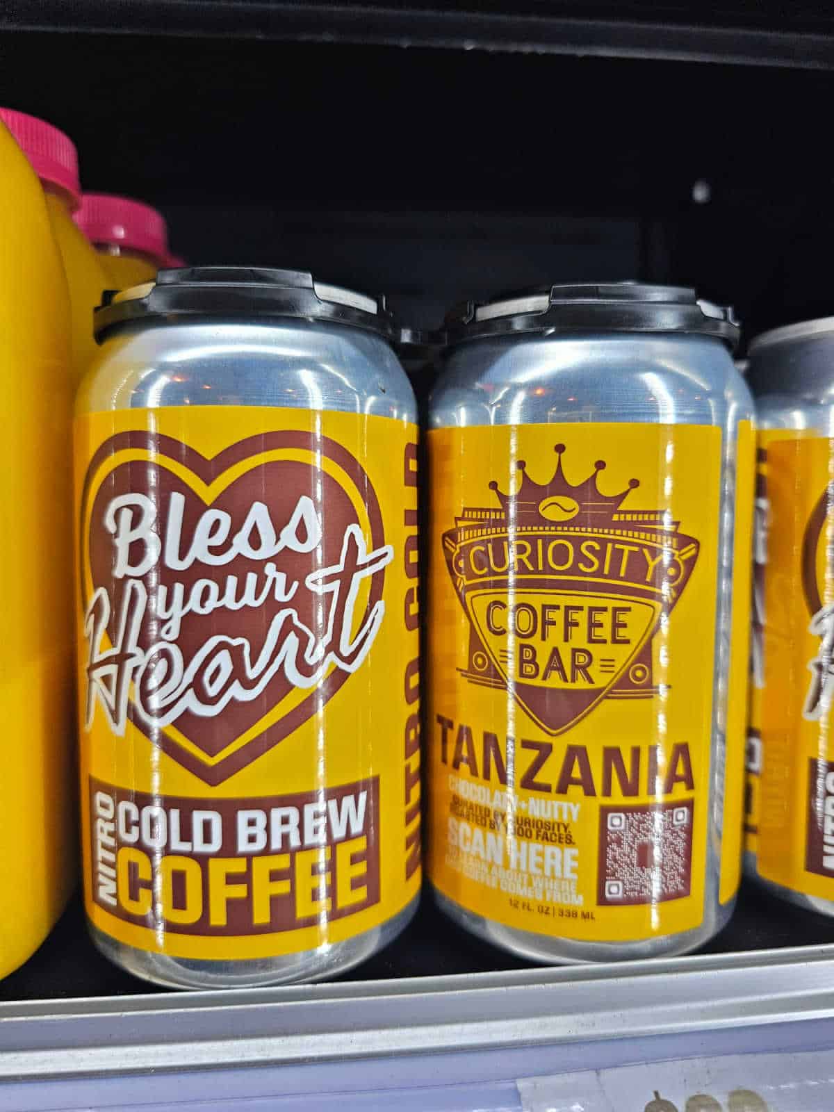 Cans of Bless your Heart Cold Brew Coffee from Curiousity Coffee Bar on a shelf