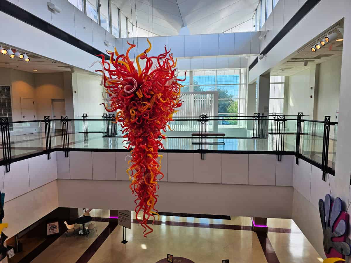 Red chihuly chandelier hanging next to the 2nd floor balcony