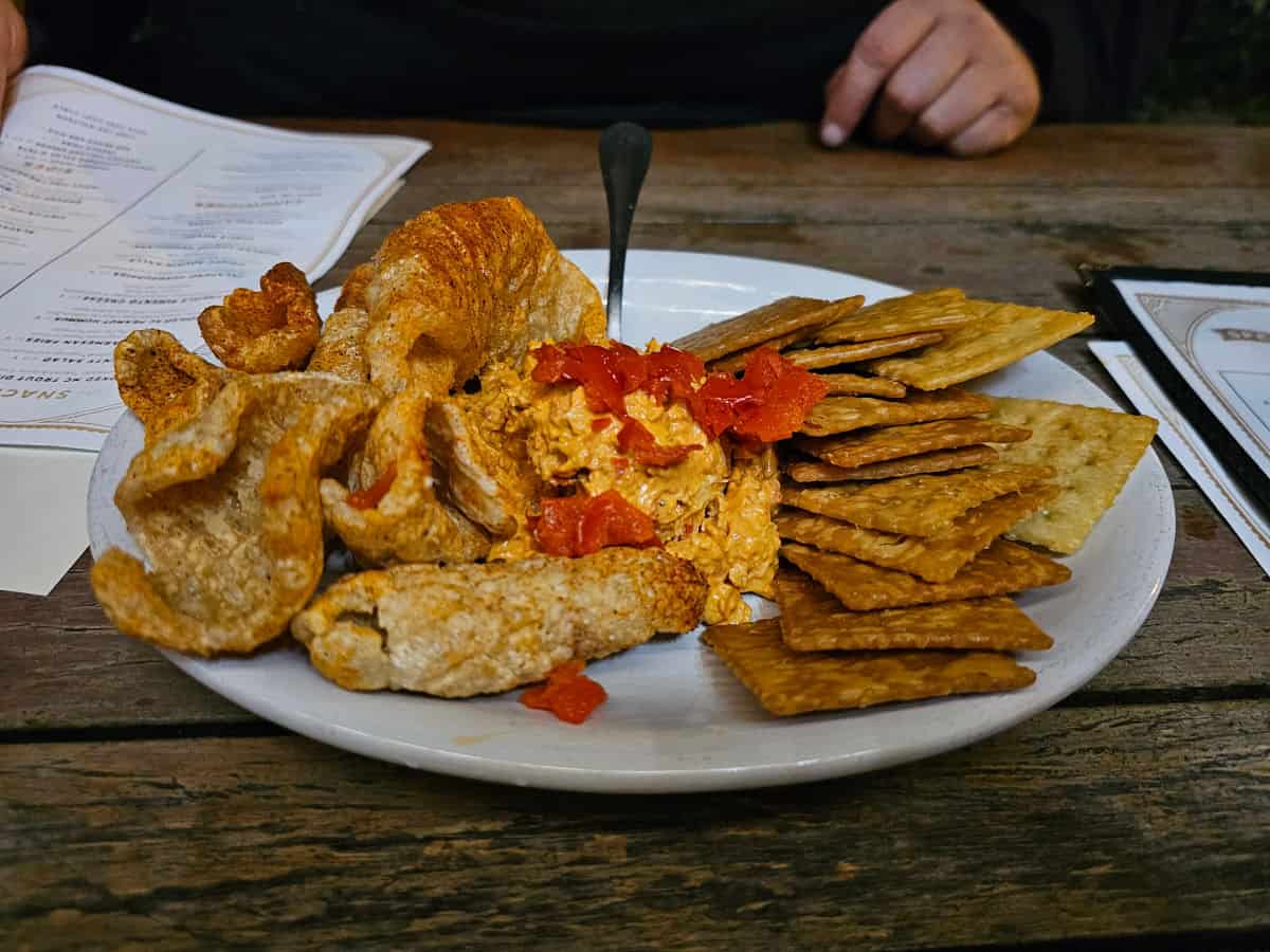 Creole pimento cheese on a plate with pork rinds and fried saltines