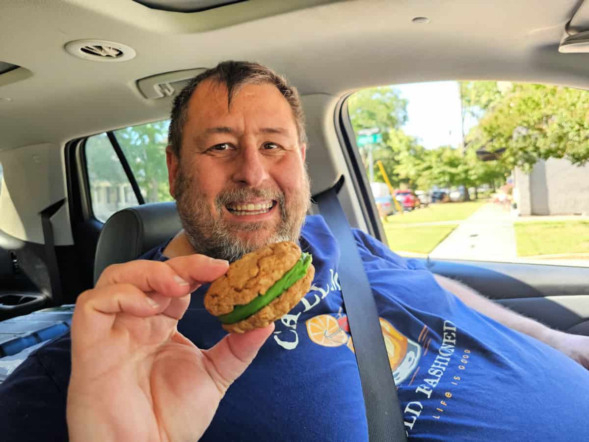 John holding a oatmeal cream pie with green icing in the car