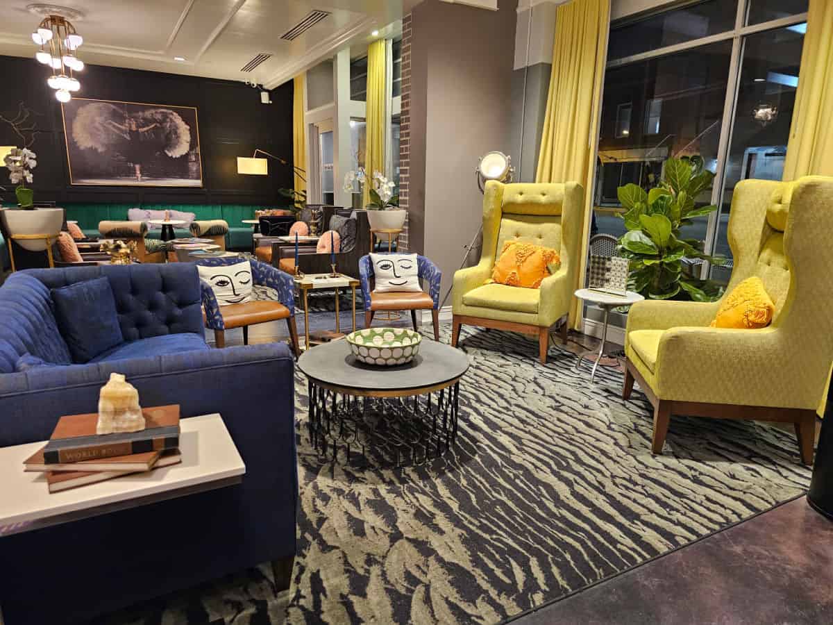 Hotel lobby with yellow chairs, blue couch, art on the all, pattern rug on the floor