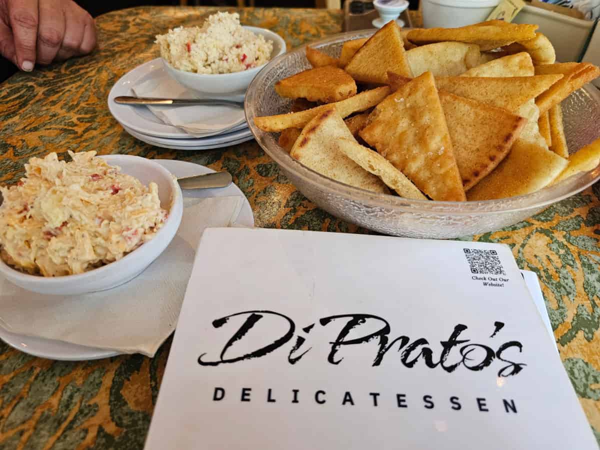 DiPrato's Delicatesan Menu next to a bowl of pita chips and two bowls of pimento cheese