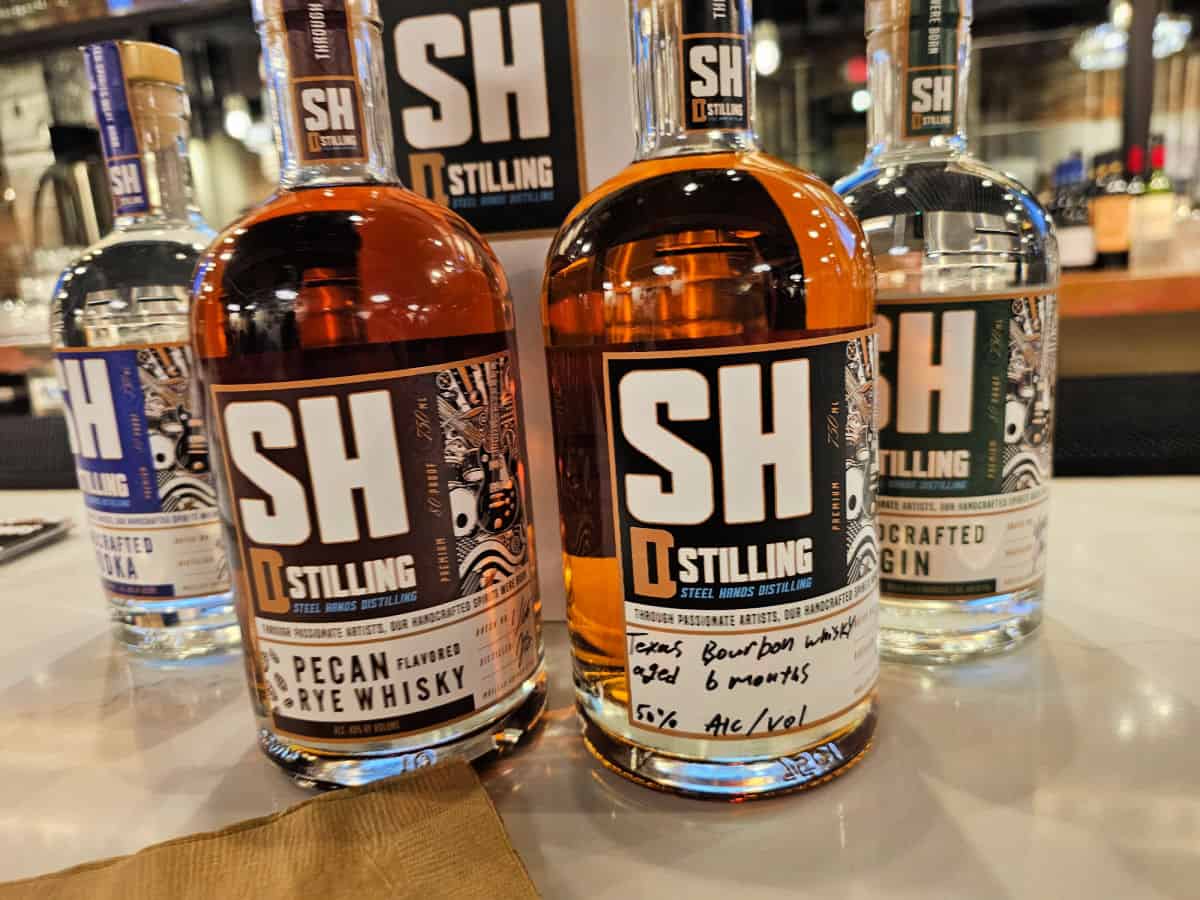 Steel Hands Distilling Pecan Rye Whiskey, Texas Bourbon, Gin, and Vodka bottles on a white counter