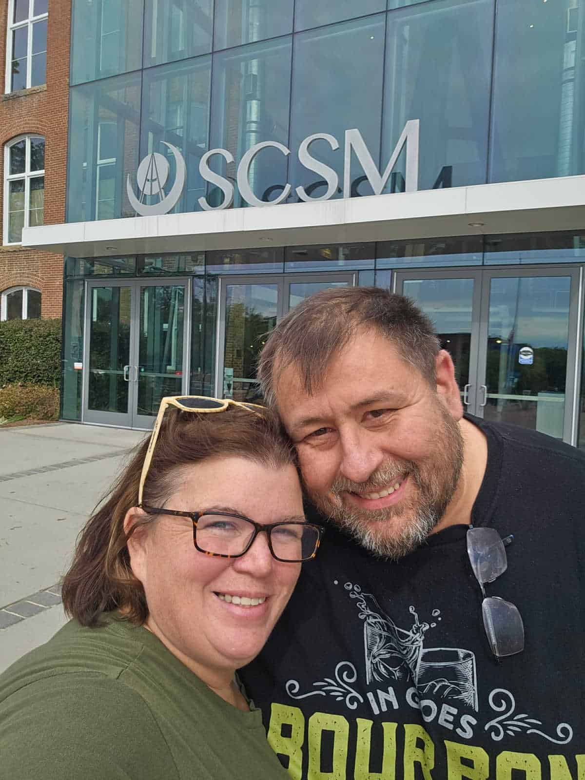 Tammilee and John in front of SCSM entrance door and sign